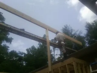 Carpenter setting a ridge beam over a new addition frame — Ice Dam Removal by Roofing Brothers in Gratis