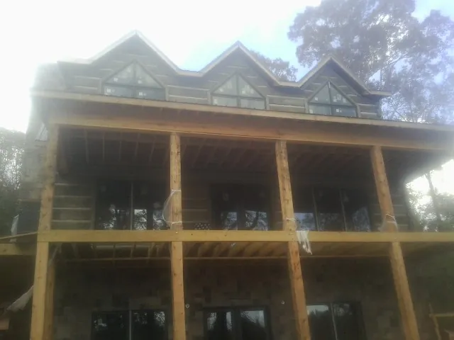 Dormers and porch framing on a large log home under construction — Roof Coating work by our crew in Gratis