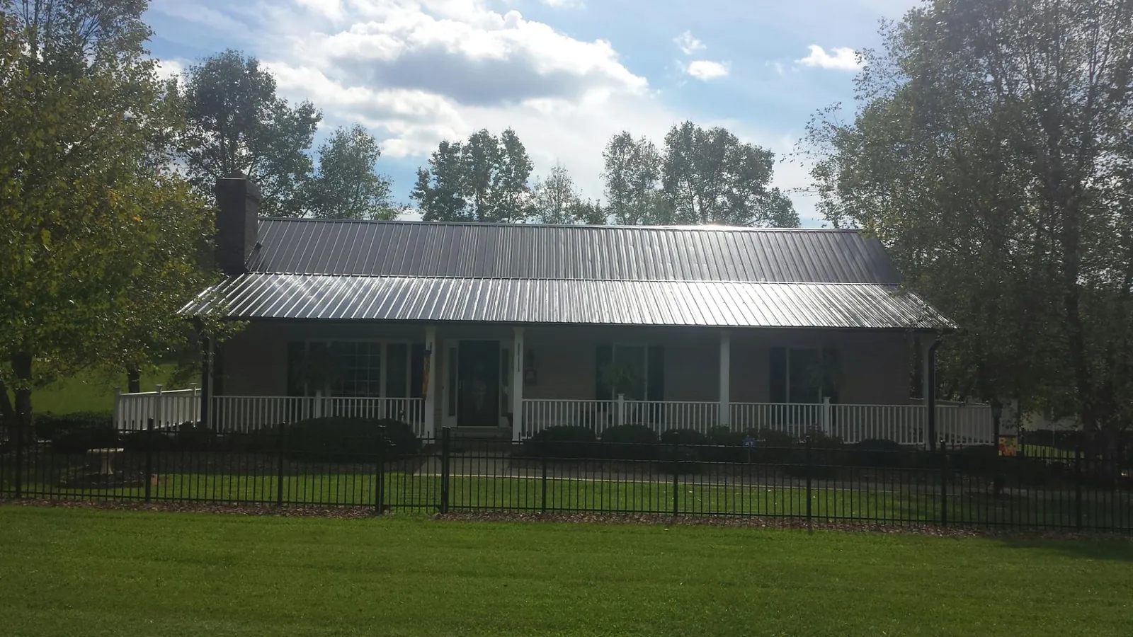 Gray metal roof on a brick ranch with a full width front porch — Gutter Guard Installation work by our crew in Gratis