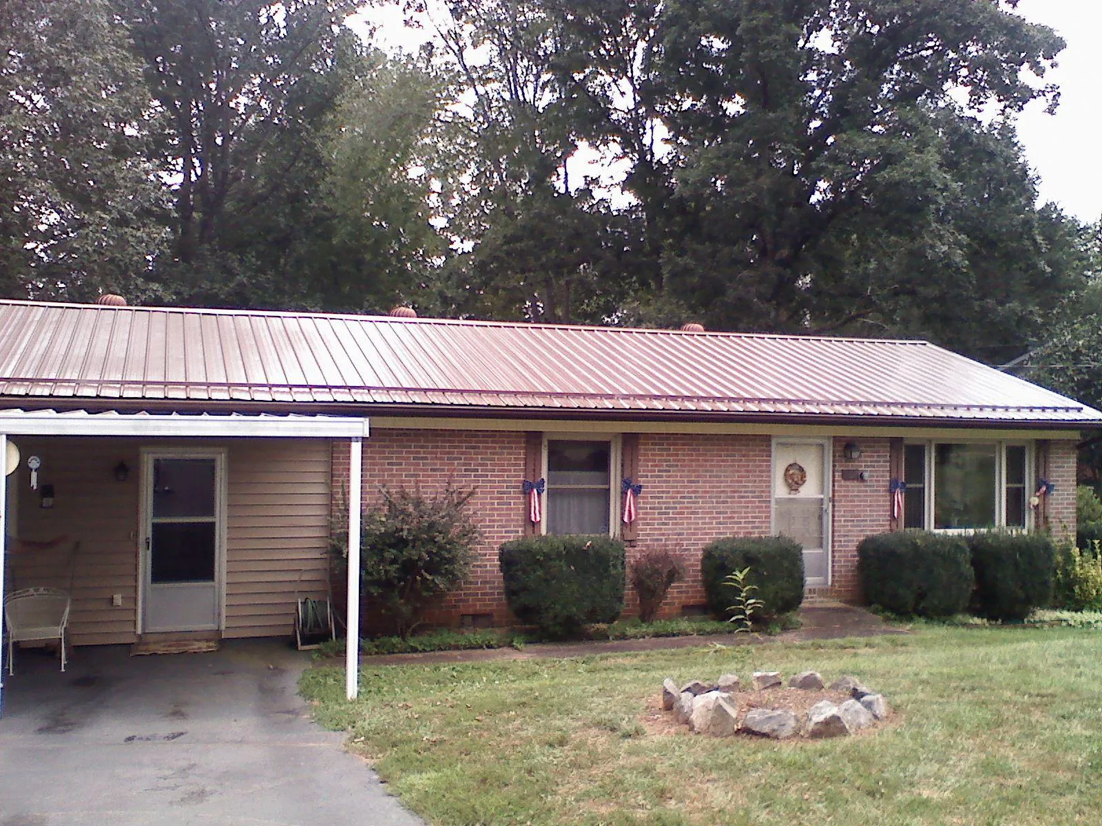 Bronze metal roof and carport on a brick ranch home — Roof Repair work by our crew in Gratis